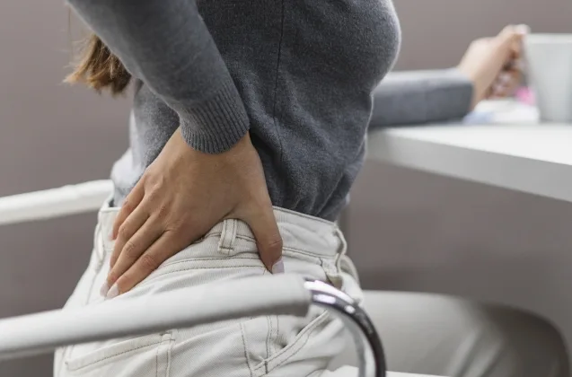 mulher sentada sentindo dor na lombar - ergonomia no home office