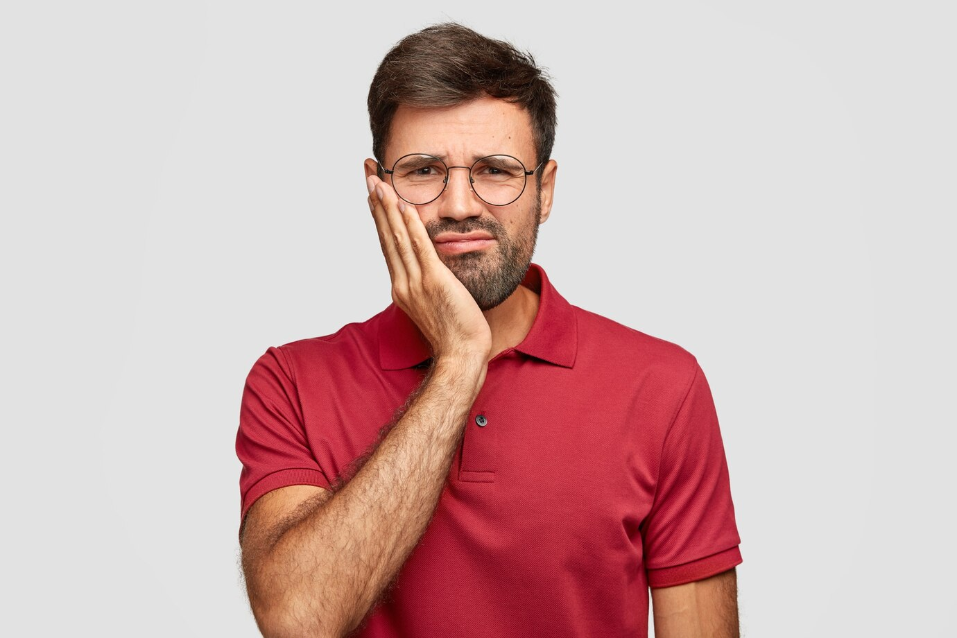 Homem de camisa vermelha com dor na face.