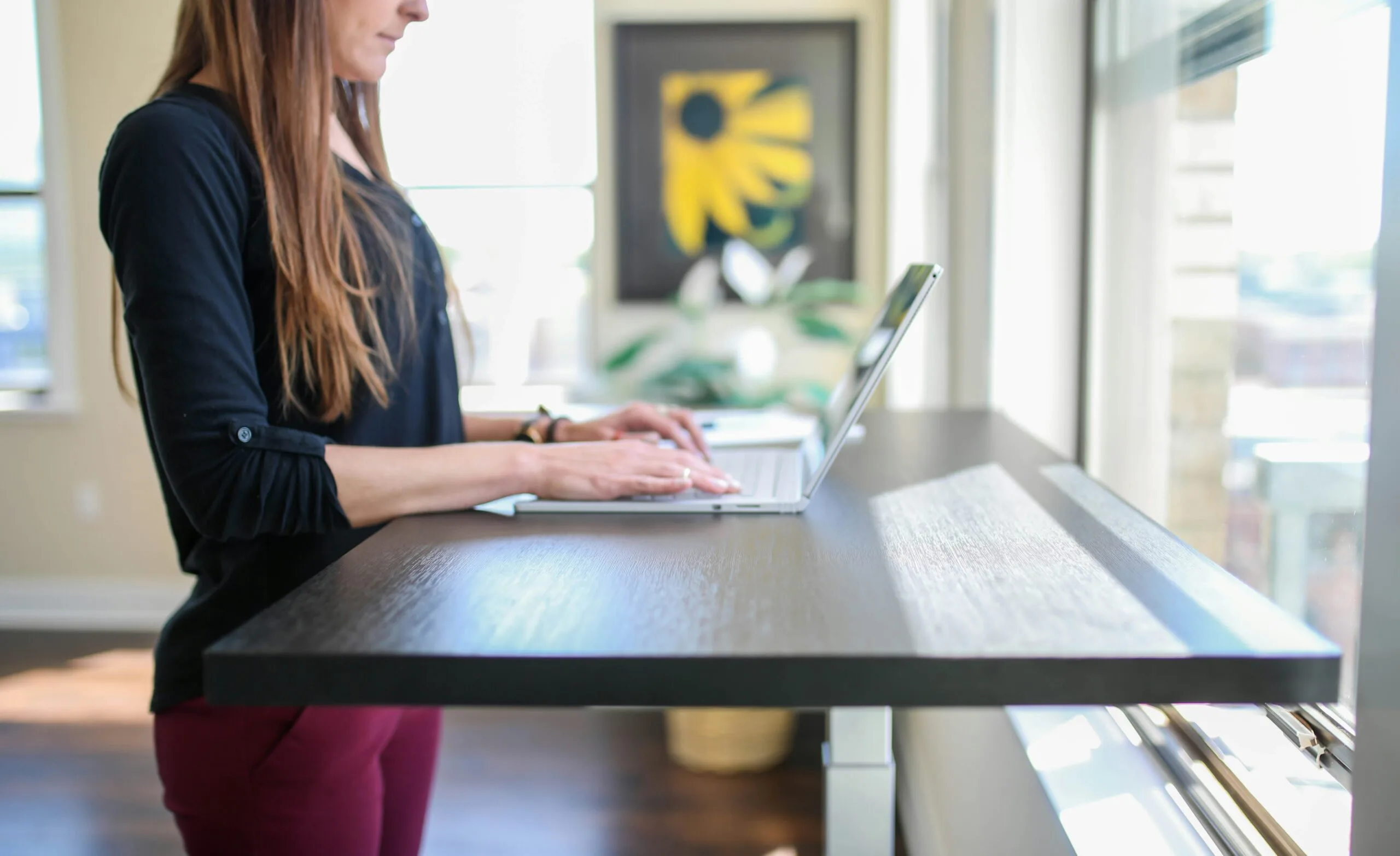 Mulher trabalhando de pé usando mesa com regulagem de altura elétrica, bela mulher em escritório, ergonomia