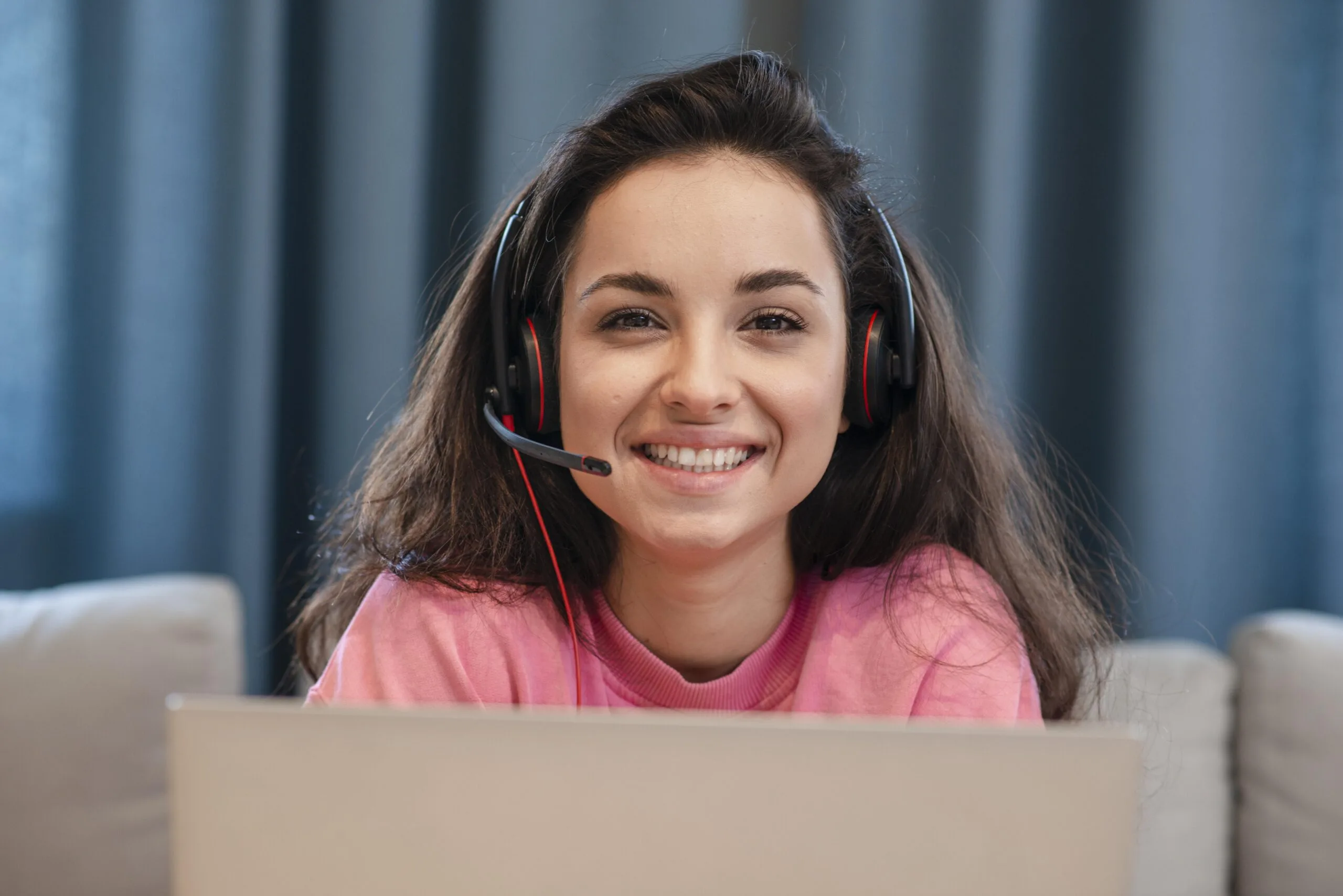Bela mulher jovem sorridente usando um headset com laptop em frente - Melhores headsets