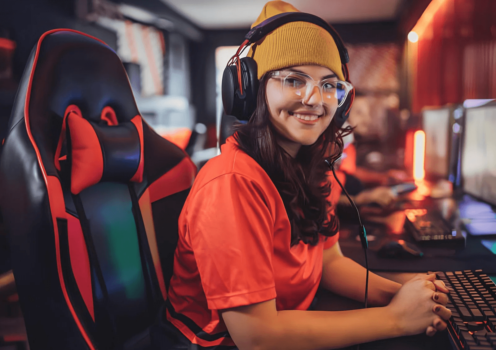 Garota gamer bela usando camiseta vermelha sentada em uma cadeira gamer vermelha - Cadeira gamer boa e barata