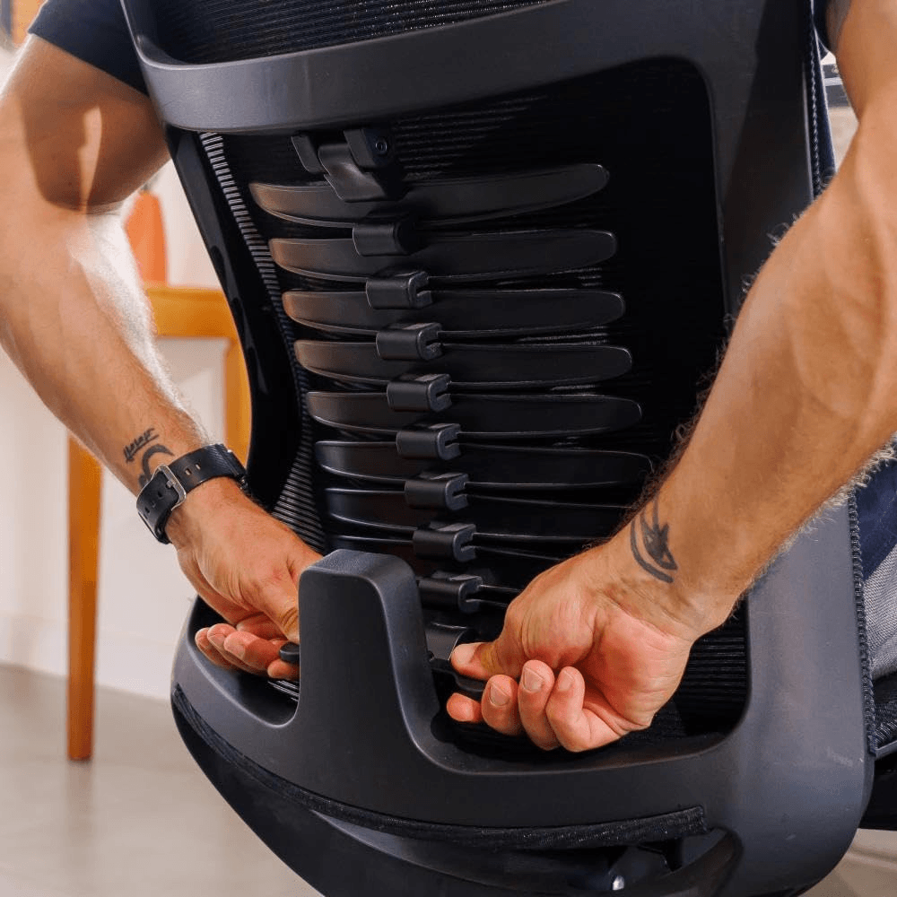 Homem forte jovem ajustando o apoio lombar da cadeira ergonômica Vertta Pro
