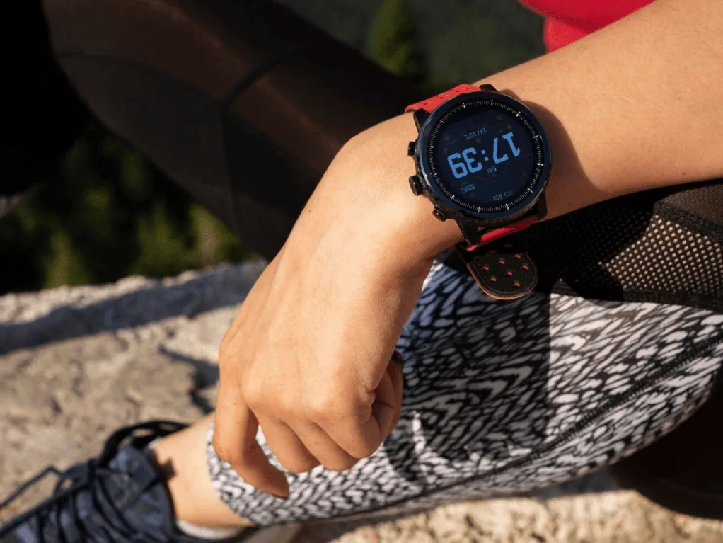 Mulher aventureira usando smartwatch Garmin com pulseira vermelha ao ar livre - Melhor smartwatch 2025